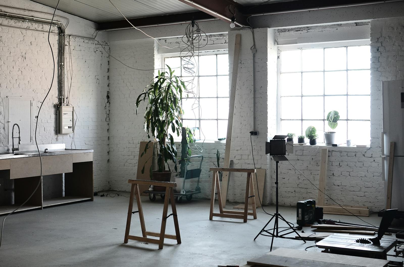 Interior of loft with brick wall with wires hanging on ceiling and tools for renovation works